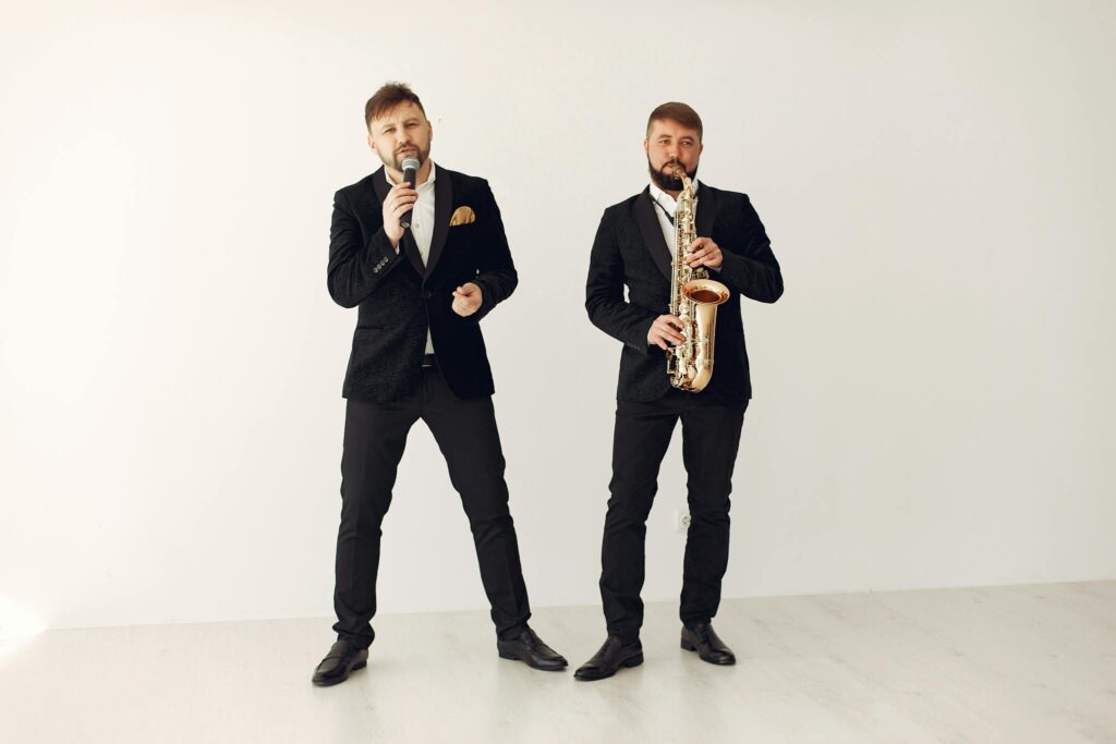 Talented male artists in elegant concert suits performing with saxophone and microphone